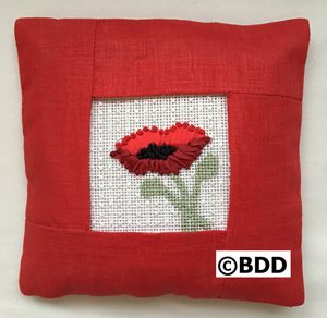 A red pillow with a flower on it.