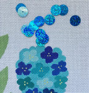 A blue flower with sequins in it's vase.