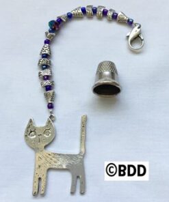 A cat charm with a thimble and bead attached to it.
