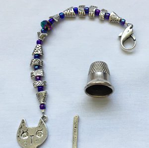 A cat charm and bead key chain with a thimble.