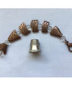 A set of seven copper colored beads and a thimble.