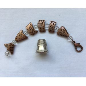 A set of seven copper colored beads and a thimble.