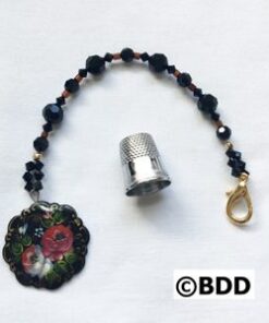 A black beaded keychain with a thimble and a rose charm.
