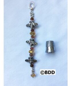 A silver charm with beads and a thimble