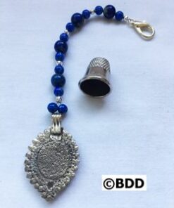 A silver pendant with blue beads and a thimble.