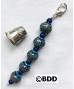 A thimble and some beads are next to a thimble.