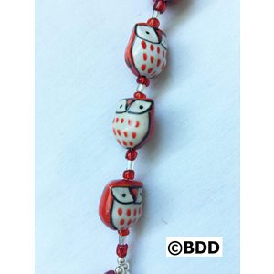 A red and white owl bracelet with a silver charm.