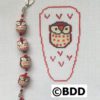 A red and white owl bracelet with a bead on it.