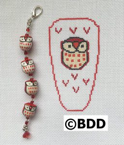 A red and white owl bracelet with a bead on it.