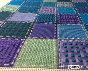 Colorful textured quilt with square patterns.
