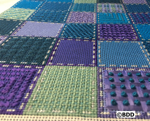 Colorful textured quilt with square patterns.