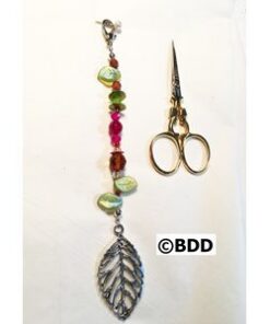 Vintage-style sewing scissors beside leaf pendant
