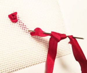 A red ribbon is tied to the end of a rose.