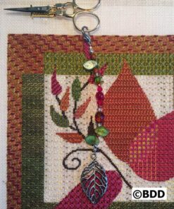 A close up of the leaf charm on a cross stitch project.