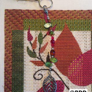 A close up of the leaf charm on a cross stitch project.