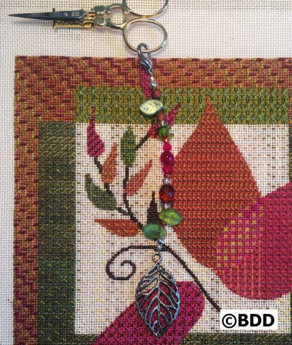 A close up of the leaf charm on a cross stitch project.