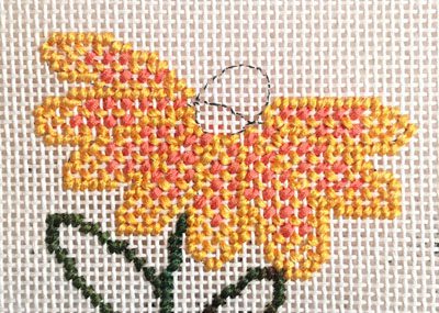 A cross stitch pattern of a flower with a needle.