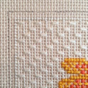 A close up of the cross stitch on a piece of fabric