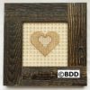 A cross stitch heart in a wooden frame.