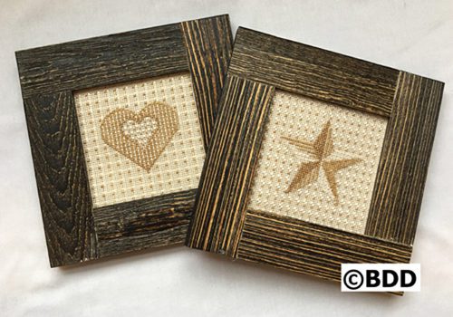 Two wooden frames with a cross stitch design in them.