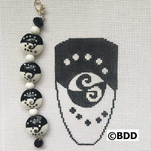 Black and white beaded charm with a design.