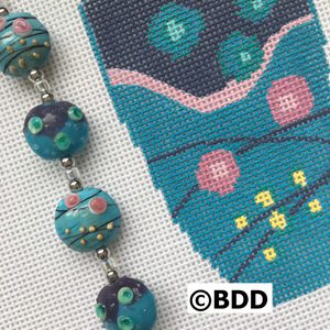 A close up of a bead on the side of a cross stitch pattern