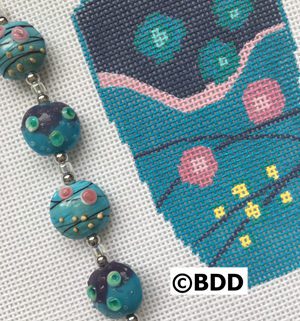 A close up of a bead on the side of a cross stitch pattern