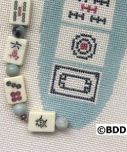 Mahjong tile beads beside stitched oval motif