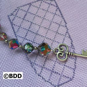 A key with a rainbow of beads on it.