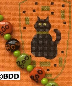 A black cat sitting on top of an orange and green background.