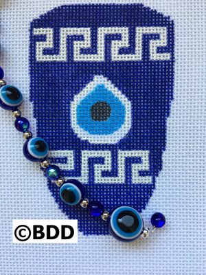 A blue and white cross stitch pattern with evil eye beads.