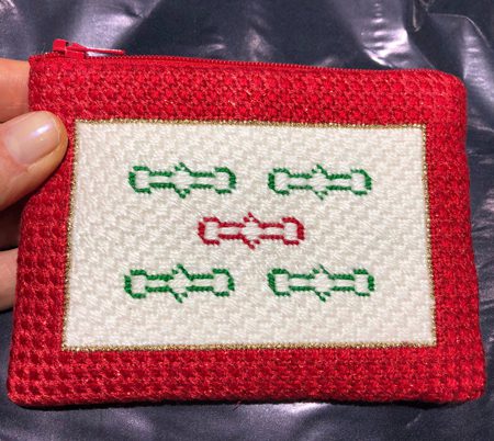 A red and white purse with green and red stitches.