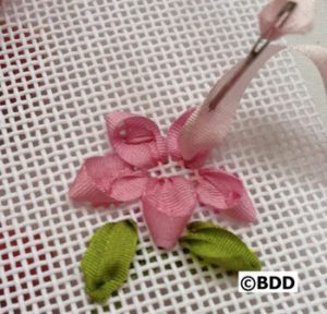 A pink flower with green leaves being cut out of it.