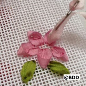 A pink flower with green leaves being cut out of it.