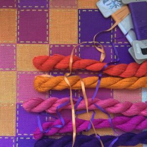 A table with several different colored yarn and a pair of scissors.