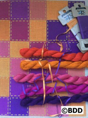 A table with several different colored yarn and a pair of scissors.