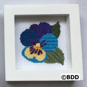 A cross stitch picture of a pansy flower.