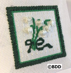 A cross stitch picture of flowers on the front.