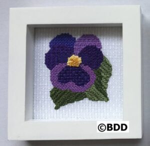 Framed needlepoint pansy embroidery.