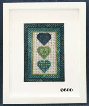 A framed picture of three hearts in green.