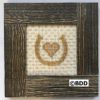 A picture frame with a cross stitch heart in the middle.