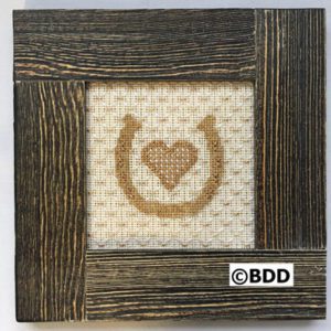 A picture frame with a cross stitch heart in the middle.