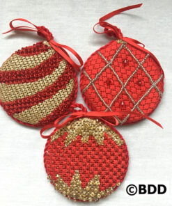 Three red and gold ornaments are sitting on a table.