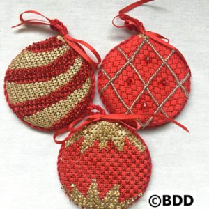 Three red and gold ornaments are sitting on a table.