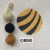 A black, white and gold bead keychain on a canvas.