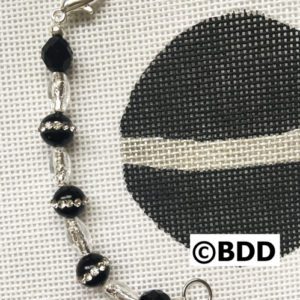 A black and white cross stitch pattern with beads.