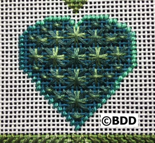 A cross stitch heart with green stitches on it.