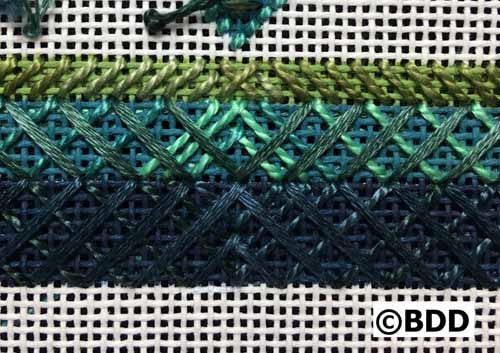 A close up of different colors of yarn on a cross stitch pattern