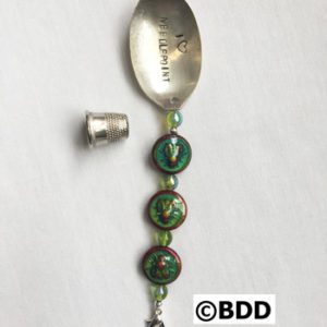 A spoon with a green bead and a silver handle.