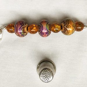 A key chain with beads and a thimble